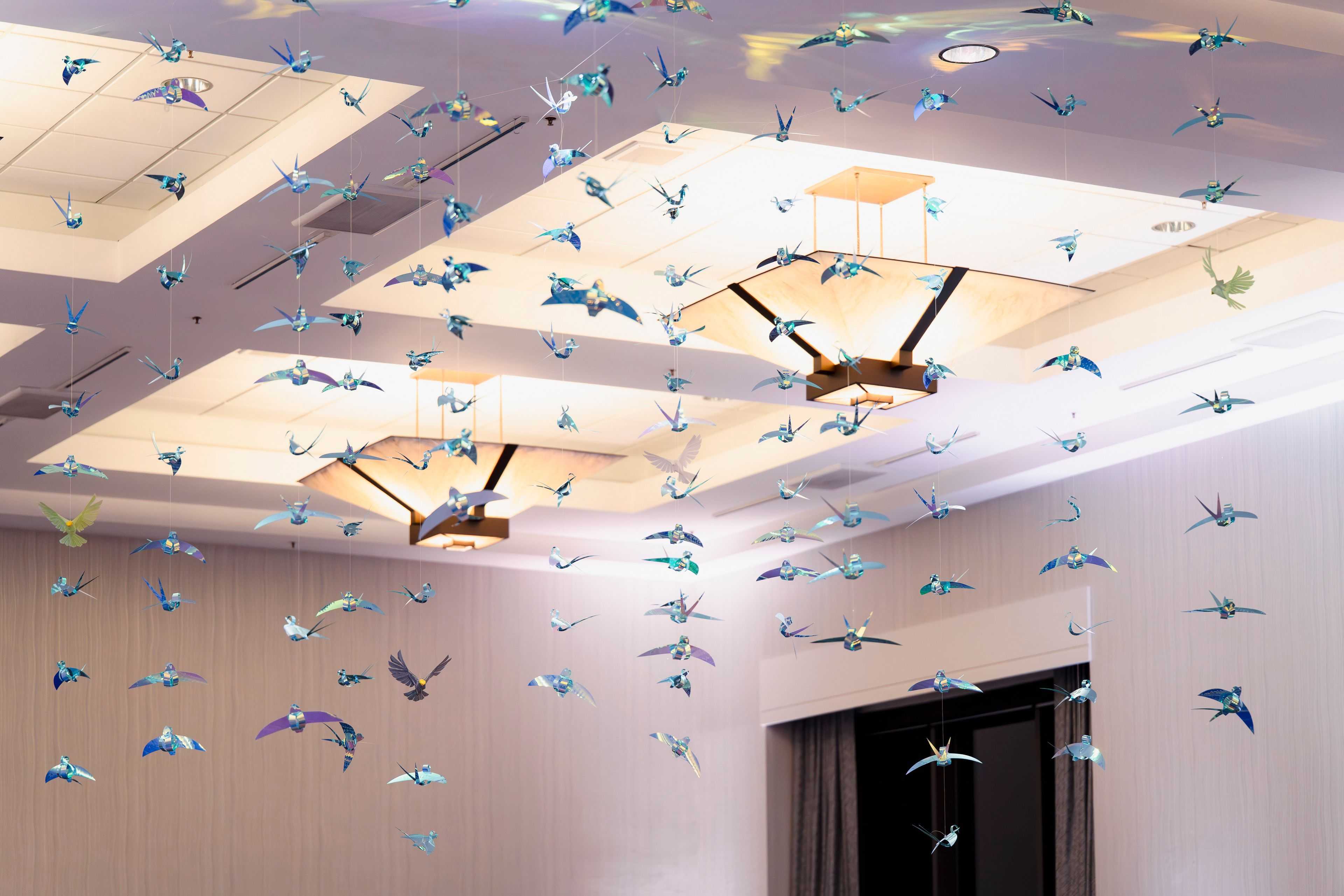 a flock of glimmering birds hanging in a ballroom