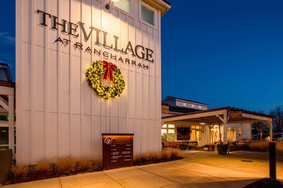 shopping center at dusk with a large wreath on a wall