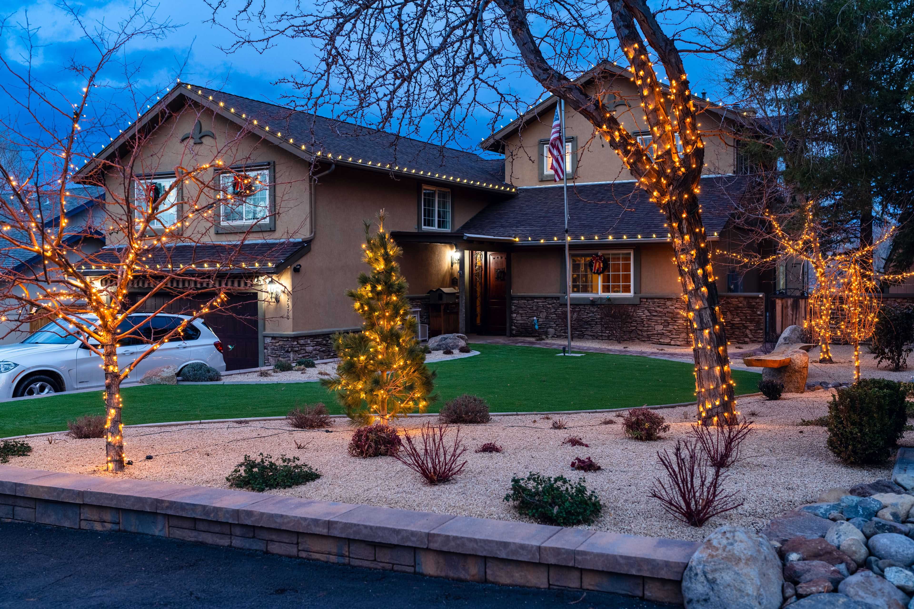 a classic Reno home thoughtfully wrapped in holiday lights including trees in the front yard