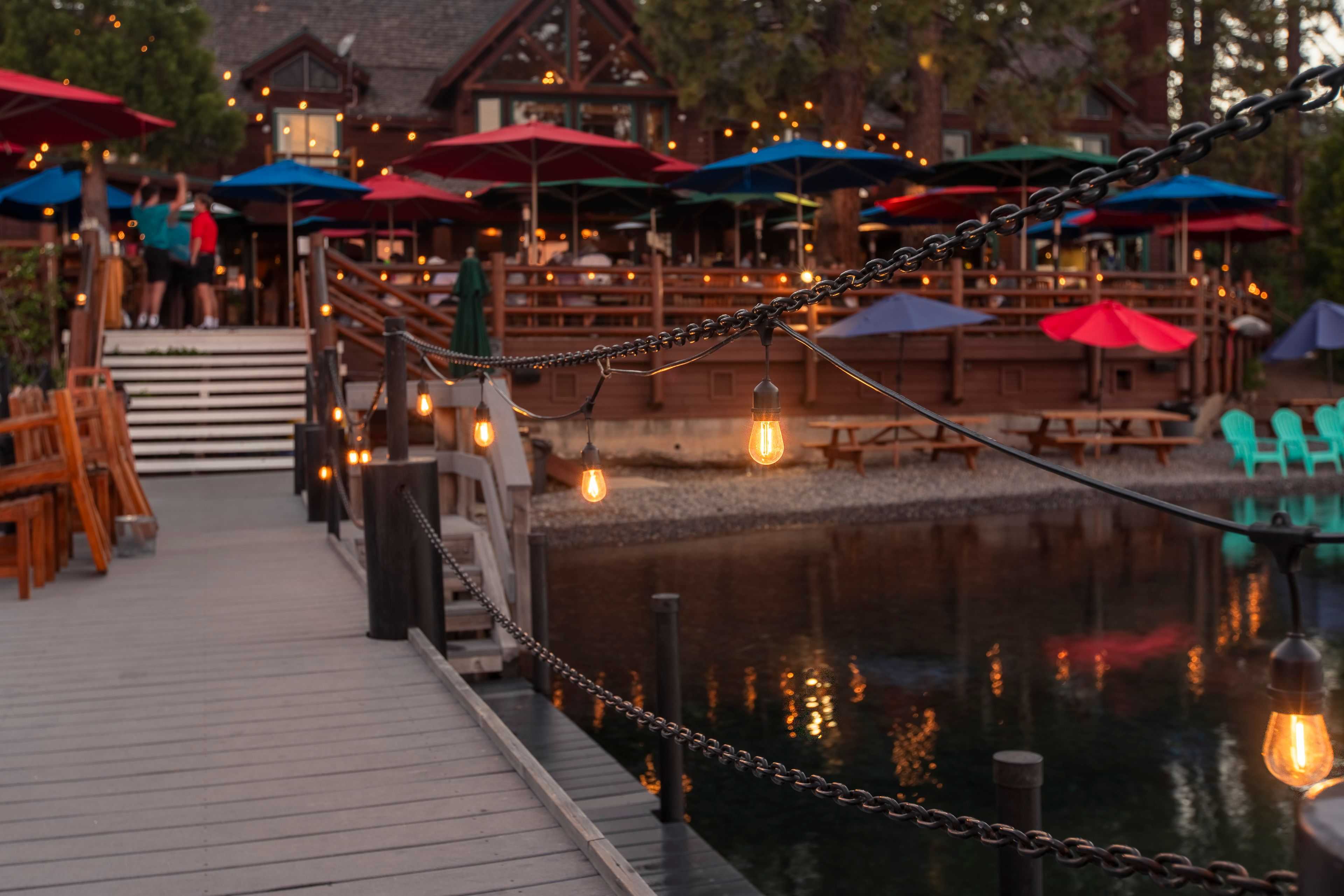 bistro lights hung by Sierra lighting hanging along a pier infront of a restaurant