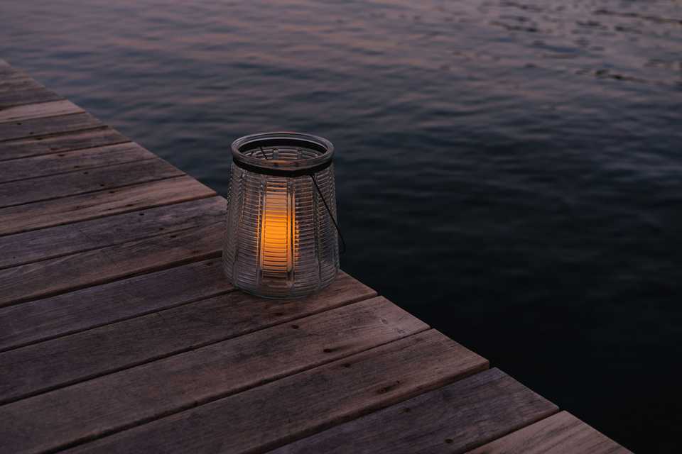 a glass lantern with a flameless candle sitting on the edge of a Tahoe pier