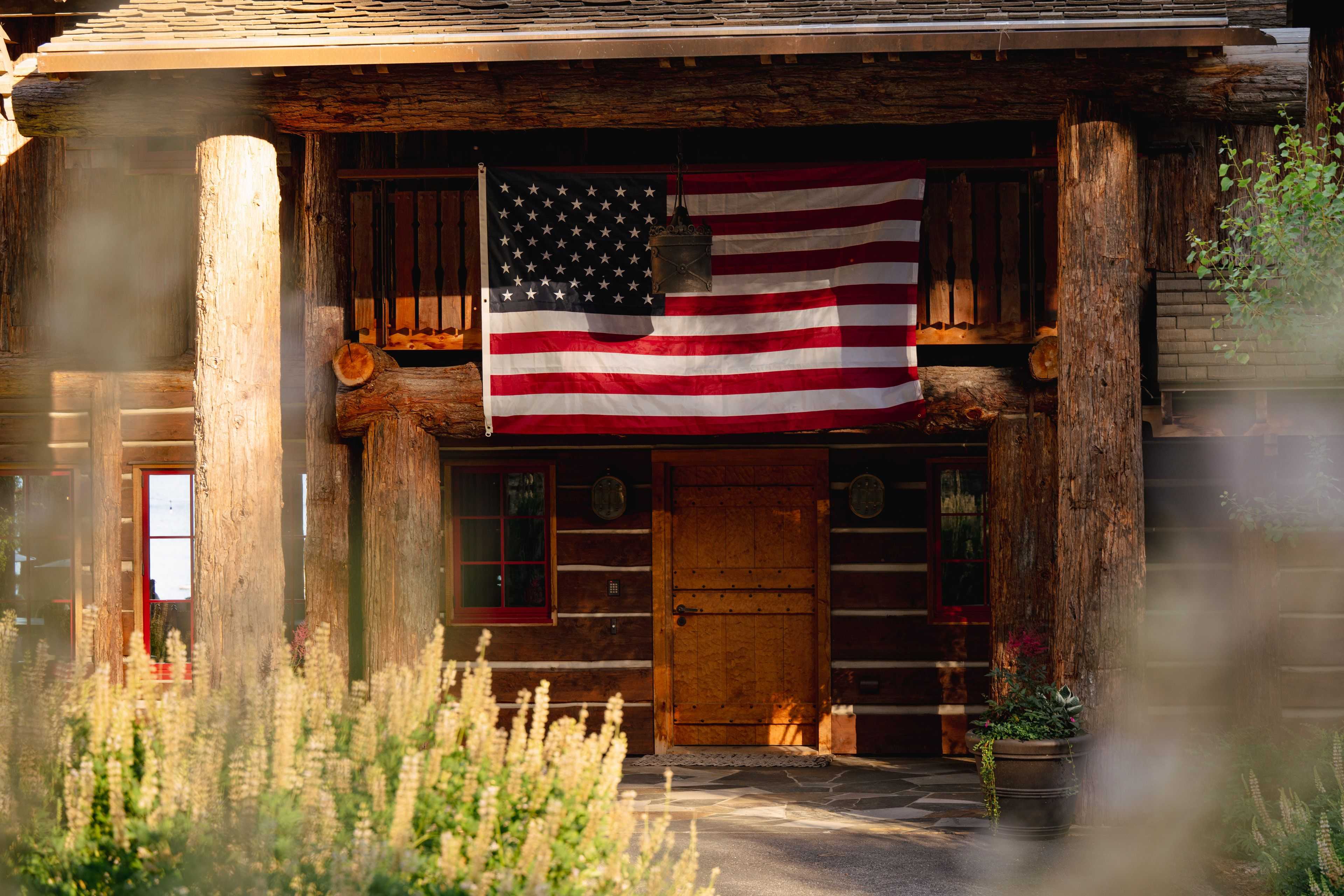 an American flag hung above a wooden homes doorway
