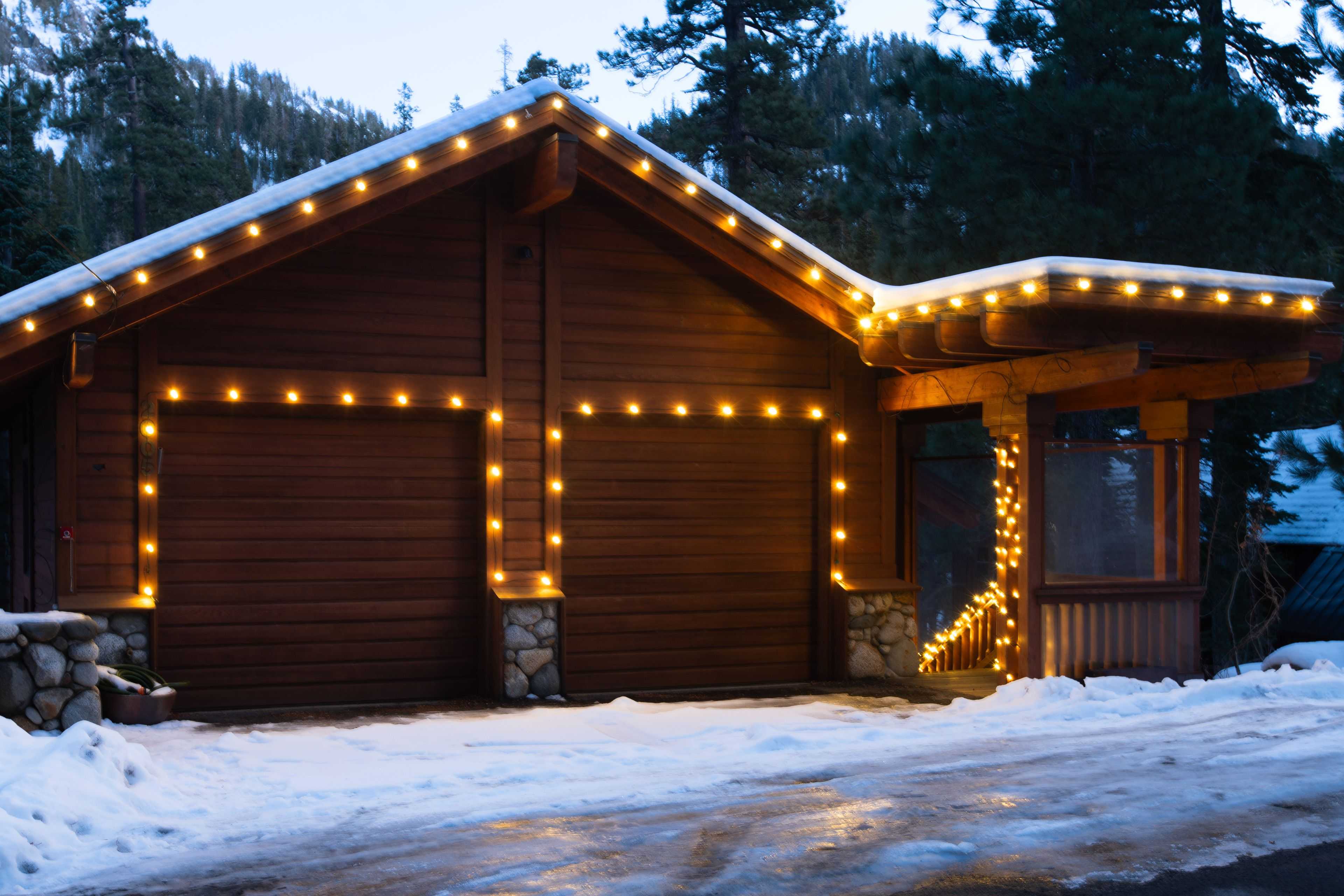 holiday lighting wrapping a garage and roofline on a house in snow