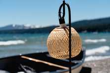 mini rattan light hanging from a shepherds hook over a canoe with Lake Tahoe behind