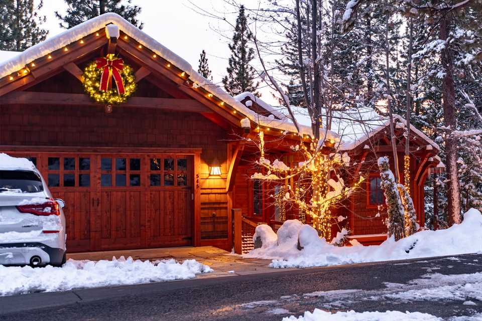 a tahoe home wrapped in Christmas lights including a wreath over the garage
