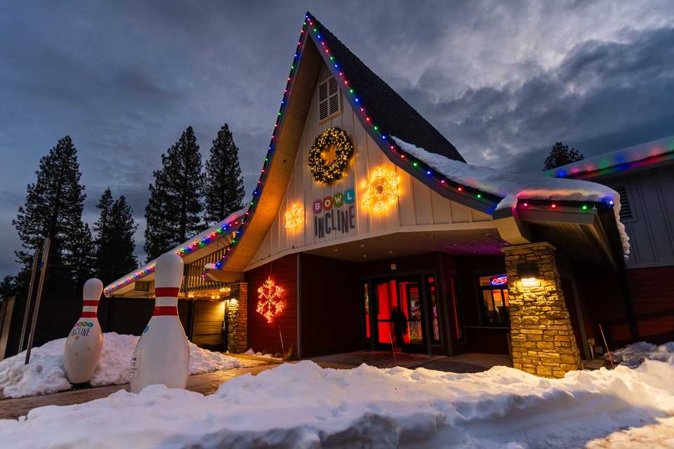 exterior of a commercial bowling alley with holiday lights at dusk