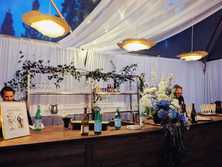 flower pendant lighting hanging above a wedding bar in a tent