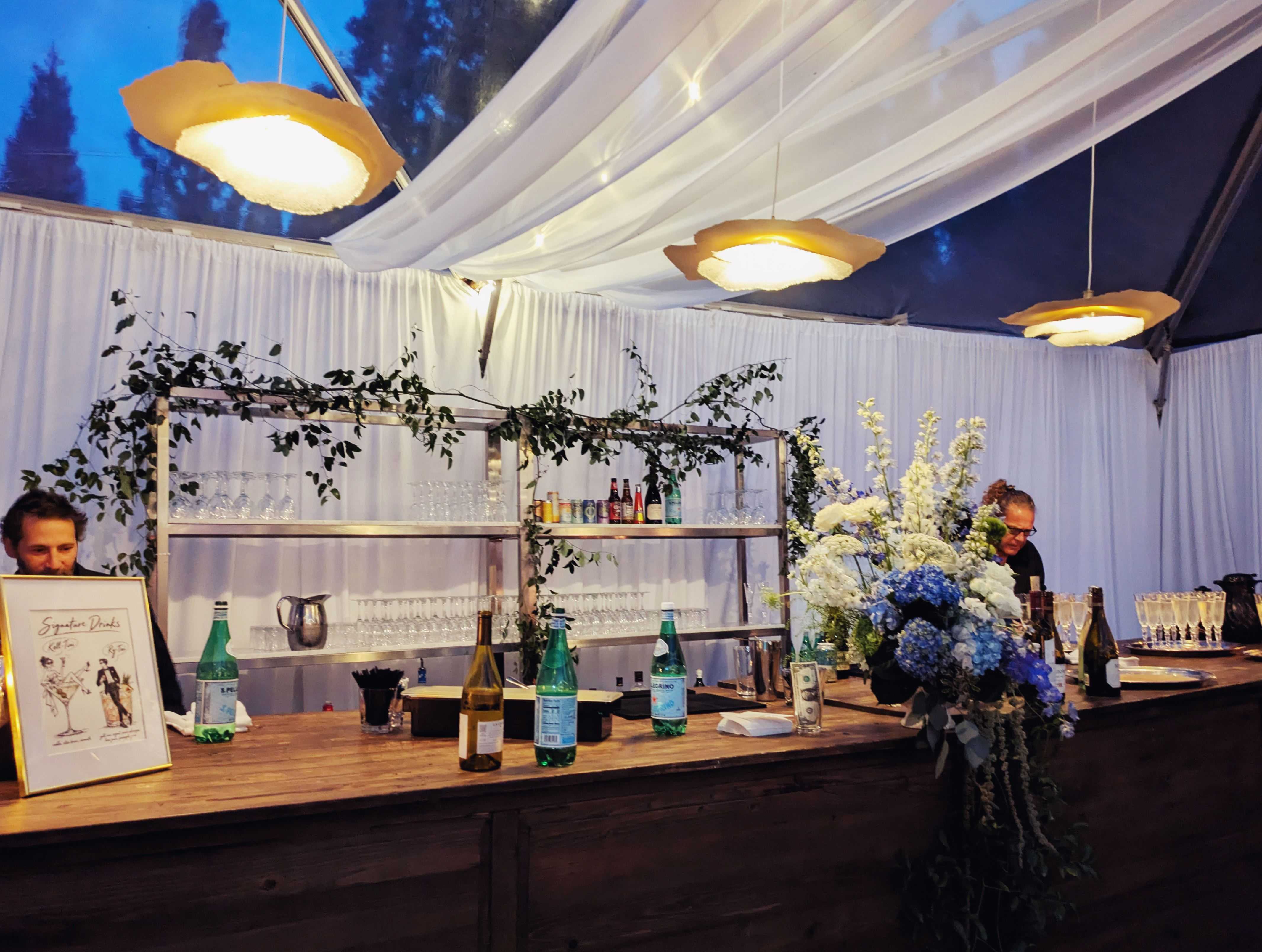 flower pendant lighting hanging above a wedding bar in a tent